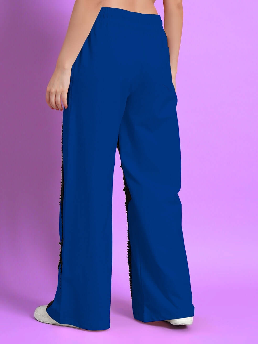 Back view of women's blue frayed textured stripes jogger pants against pink background.
