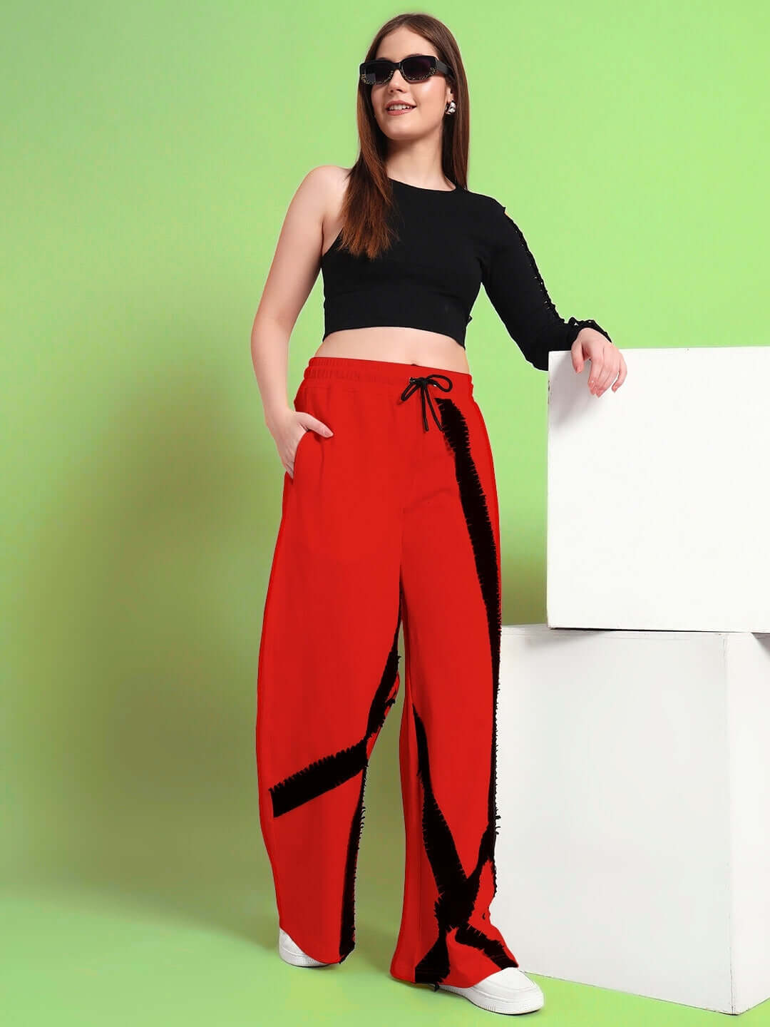 Woman wearing red frayed textured stripes jogger with black top against a green backdrop.
