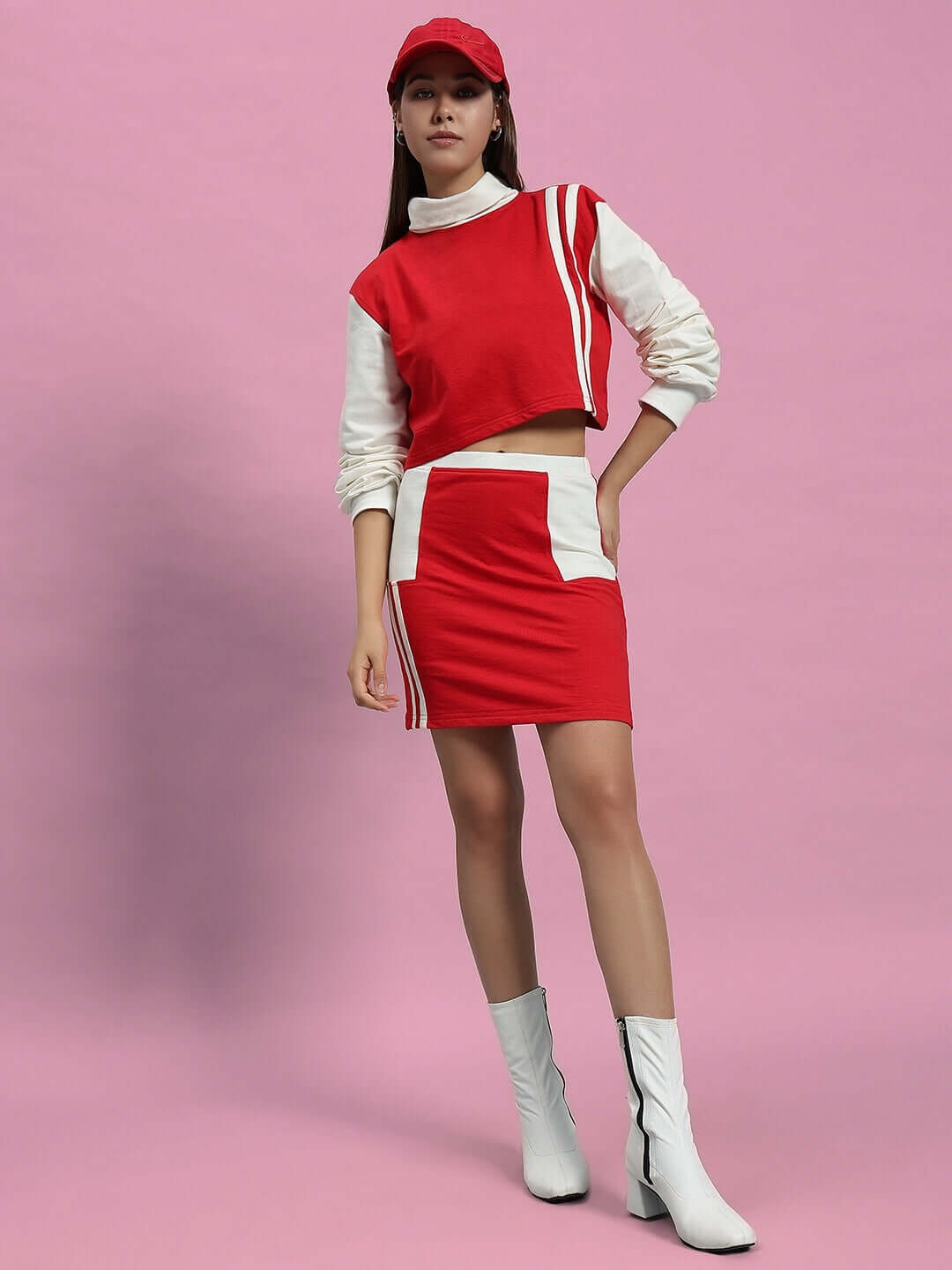 Woman wearing WOMEN FREYA CO-ORD SET OFF WHITE RED, stylish red and white ensemble with sporty elements against a pink background.