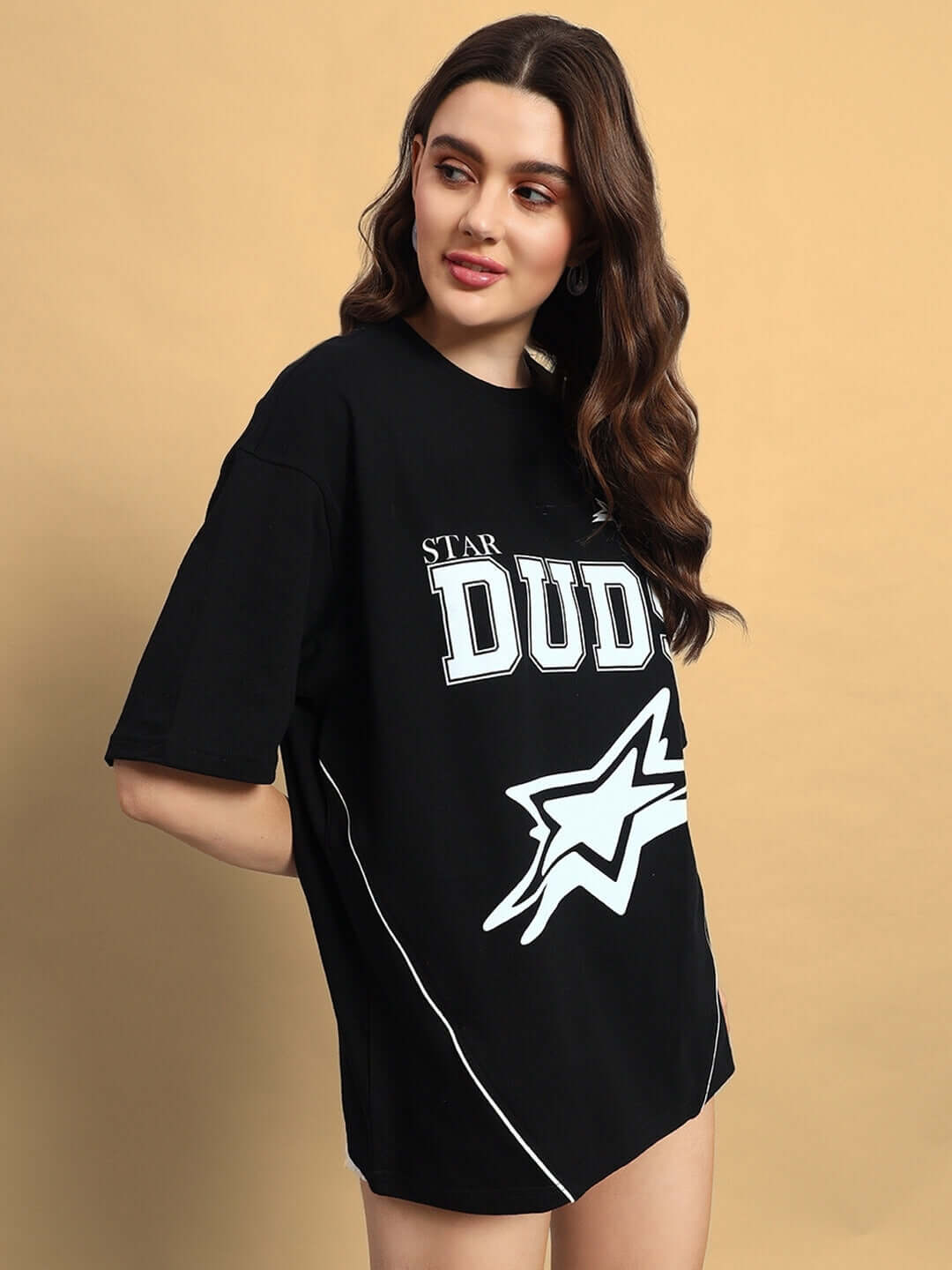 Woman wearing a black oversized T-shirt with galaxy star design and 'DUDS' lettering, offering custom fit options.
