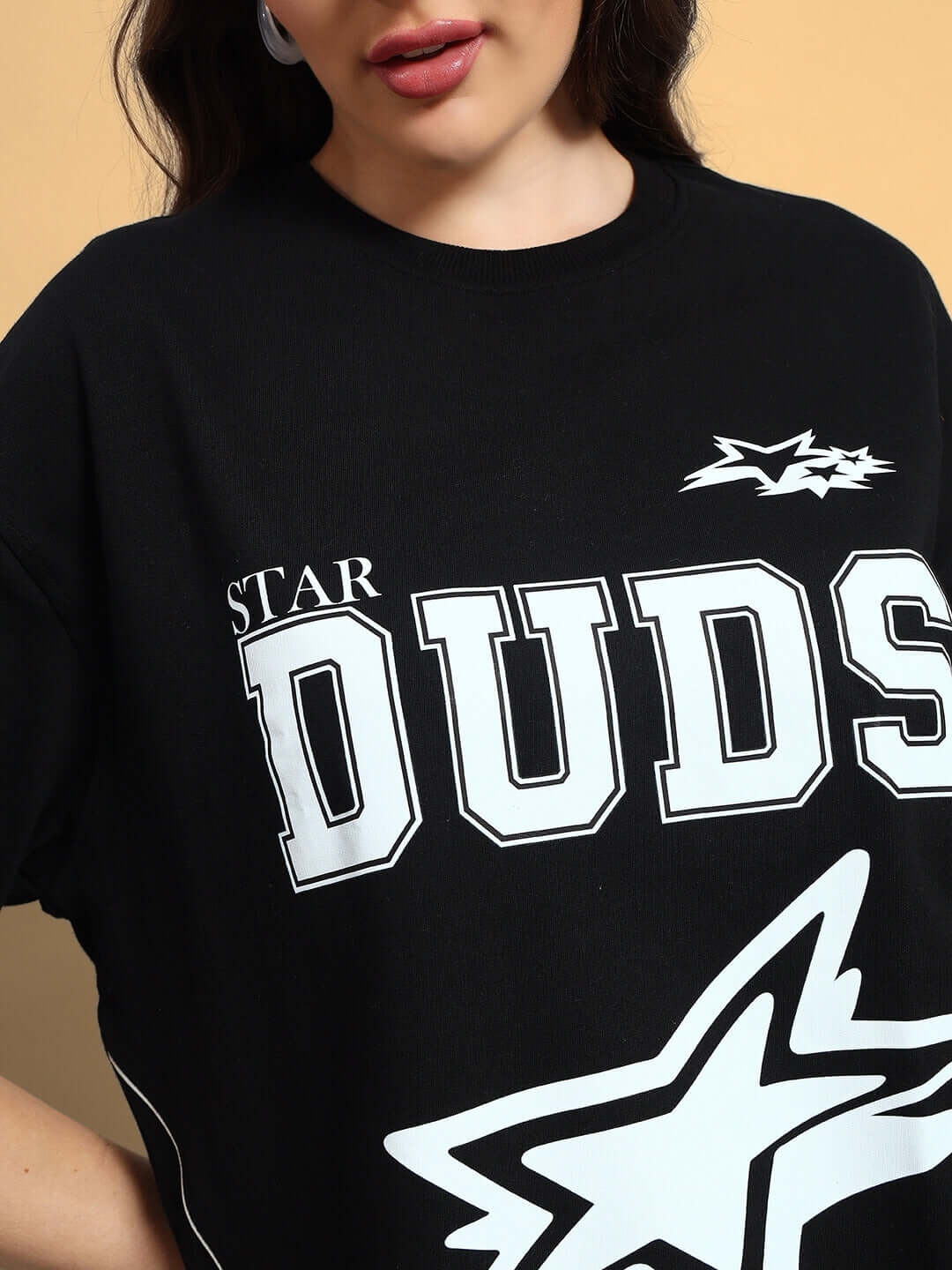 Close-up of a woman's black oversized t-shirt with 'STAR DUDS' print, showcasing stylish design, available with custom fit options.