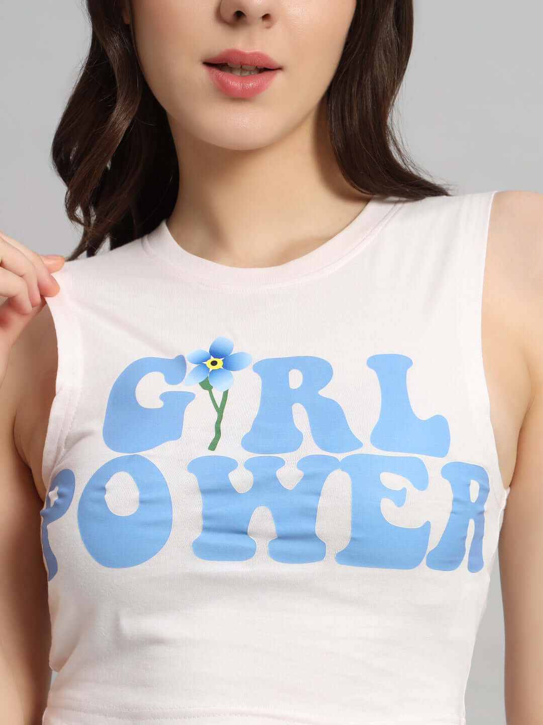 Woman wearing a baby pink tank top with 'Girl Power' print in blue, made from premium cotton with a floral design.