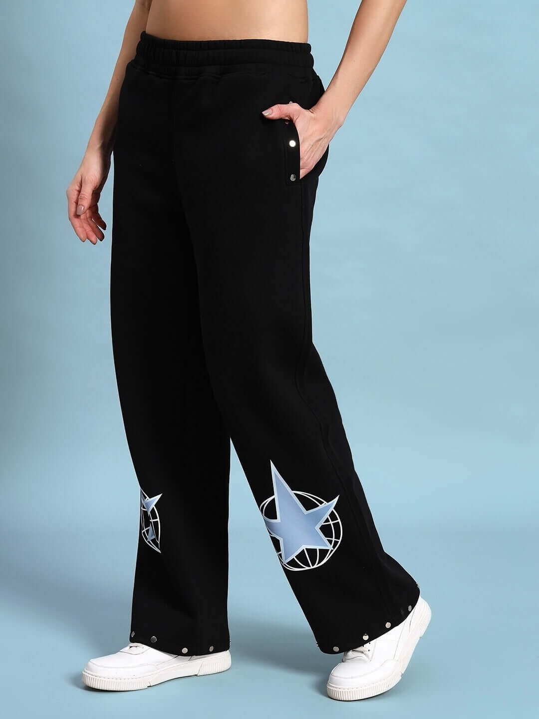 Model wearing WOMEN GLOBAL FLEECE CO-ORD BLACK pants with star design, showcasing streetwear style and comfort.