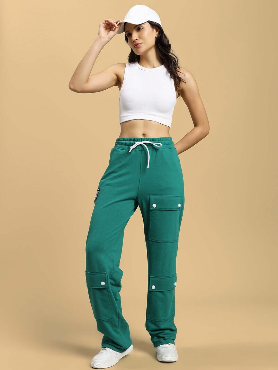 Model wearing WOMENS AWESOME FLAP POCKET BAGGY JOGGER GREEN, paired with a white crop top and cap, showcasing streetwear style.