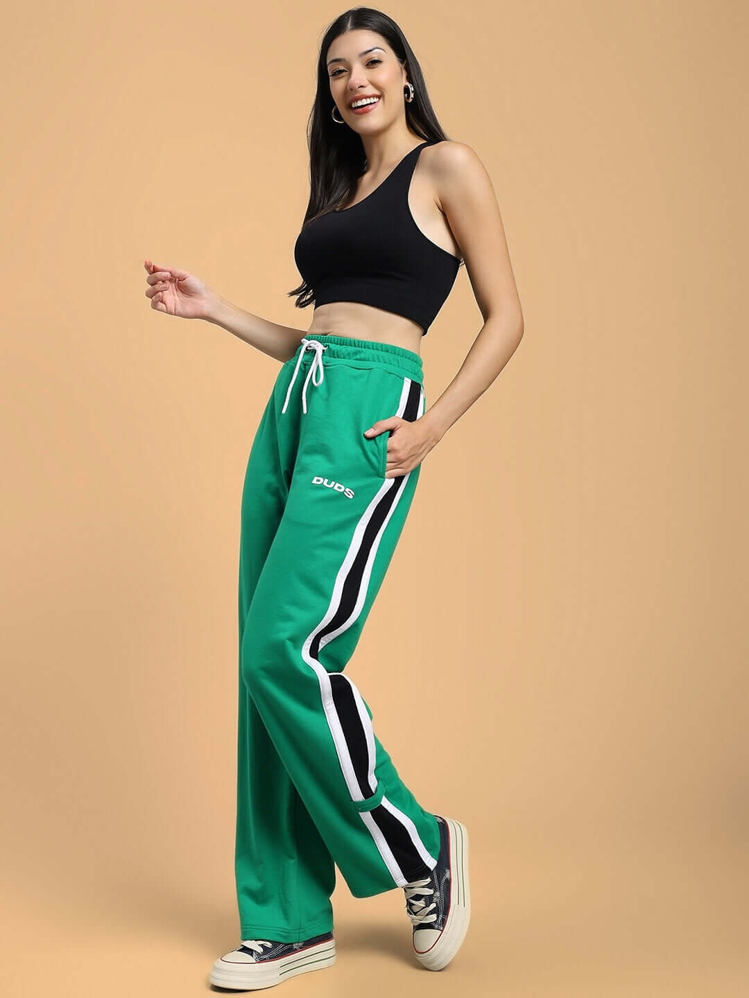 Model wearing WOMEN'S ROSSTON Flat-Out Relaxed Fit Joggers in green by DUDS with side stripes, styled casually with a black tank.