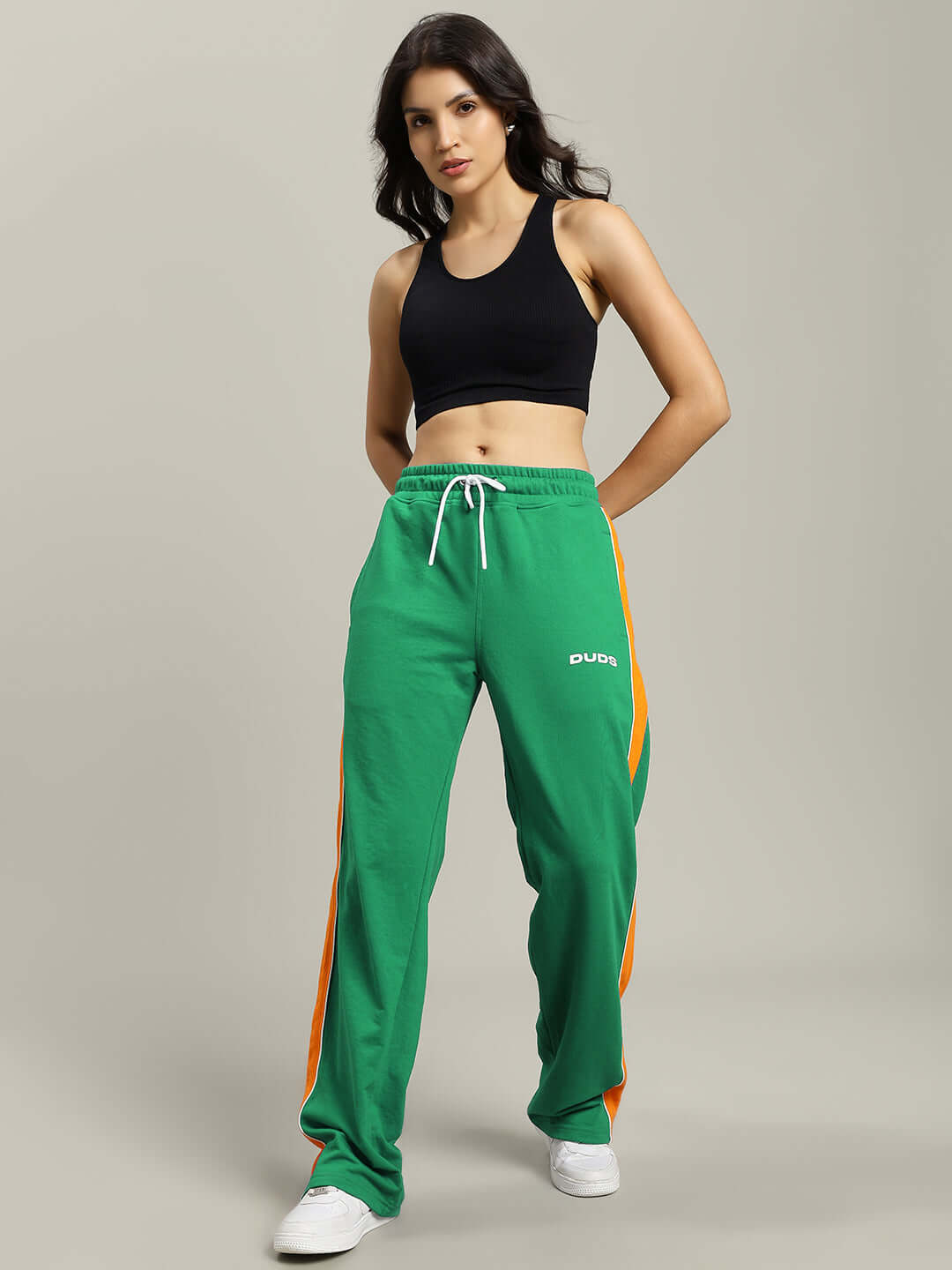 Woman wearing WOMENS SANFORD STRIPE JOGGERS GREEN with orange side stripes, stylish and relaxed fit, perfect for casual outings, soft fabric.