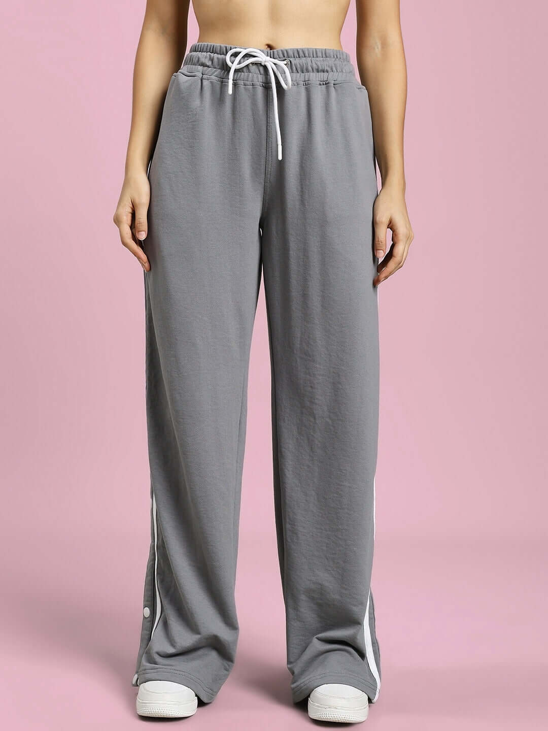 Woman wearing grey contrast panel jogger pants with drawstring, styled casually against a pink background.
