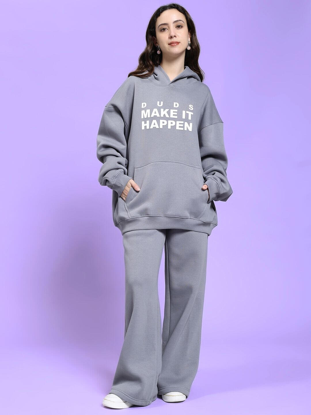 Model wearing WOMEN MAKE IT HAPPEN FLEECE CO-ORD SET GREY showcasing cozy style perfect for lounging and streetwear on a purple background