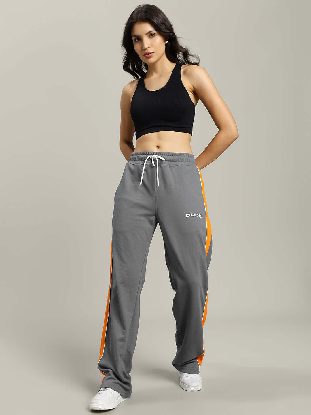 Woman wearing WOMENS SANFORD STRIPE JOGGERS GREY with orange side stripes, showcasing stylish and comfortable activewear.