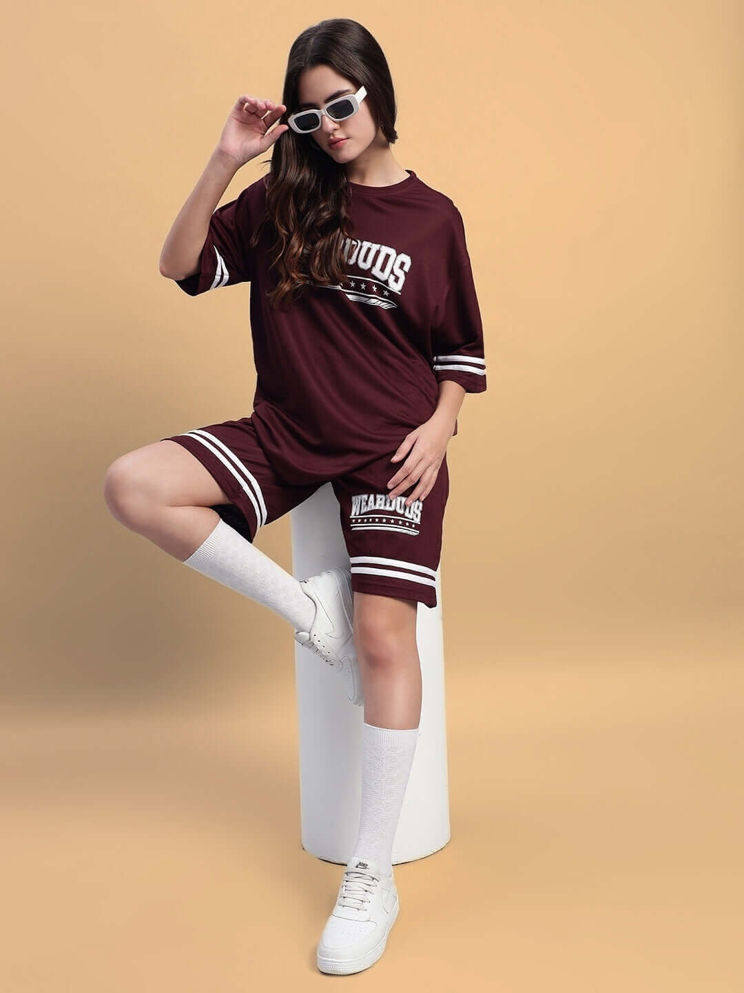 Woman wearing WOMEN'S GROOVY COLORBLOCK CO-ORD SET WINE in a stylish pose with sunglasses on a beige background.