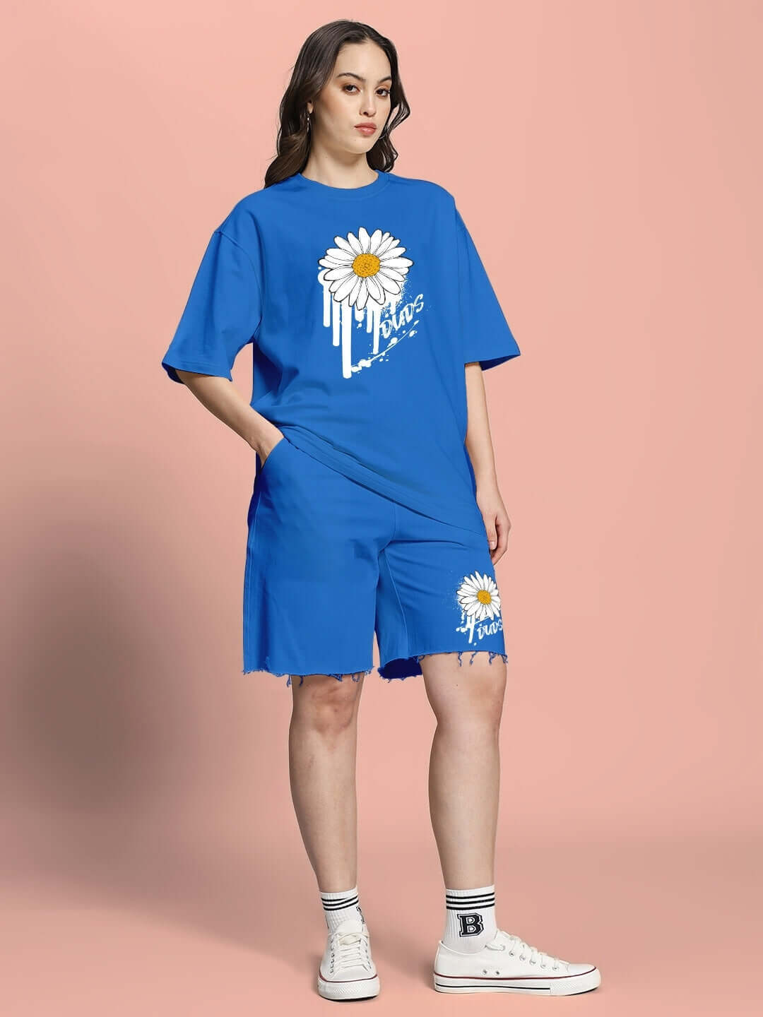 Woman wearing WOMEN'S HELIANTHUS SUMMER CO-ORD SET BLUE with daisy print against a peach background.