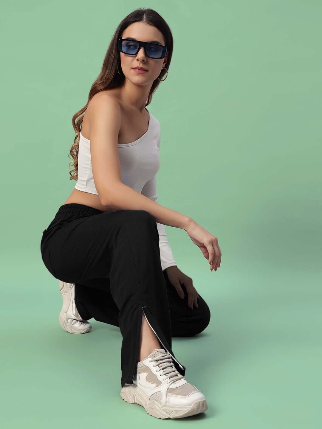 Woman wearing Hershey side slit joggers in black paired with a white top and sunglasses, showcasing stylish comfort and modern fashion.