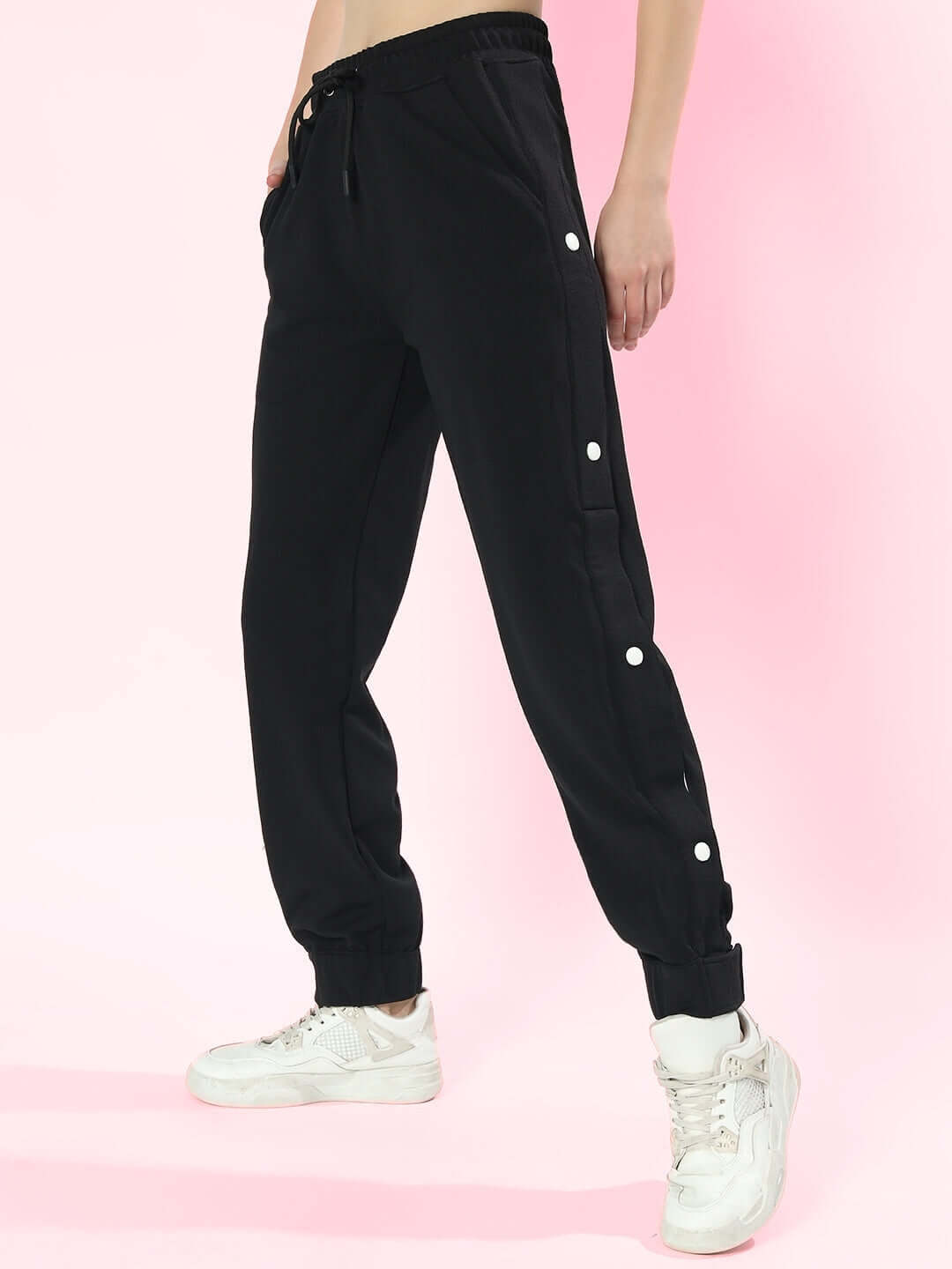 Black women's hip hop joggers with button detail, showcased against a pink background, perfect for a custom fit, made by DUDS.