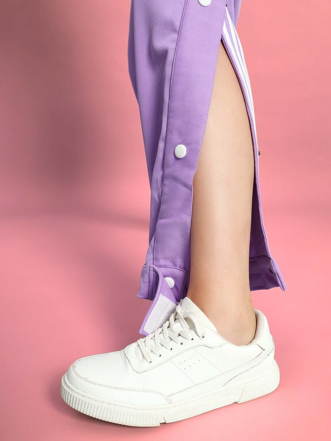 Lavender women's hip hop joggers with white sneakers on pink background, showcasing button detail.
