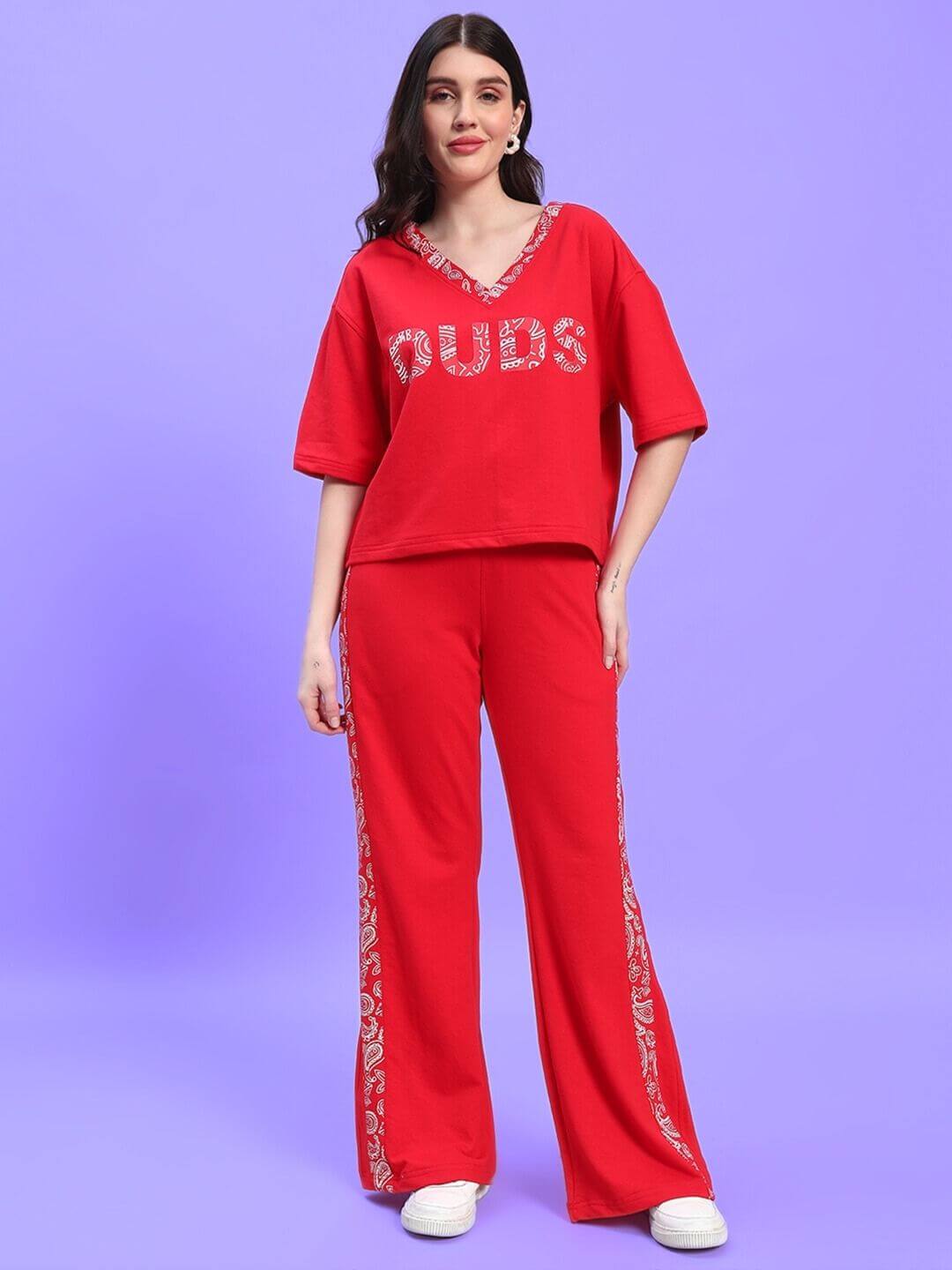 Woman wearing red WOMEN'S HOLLY CO-ORD SET - RED with bold lettering, standing against a purple background.