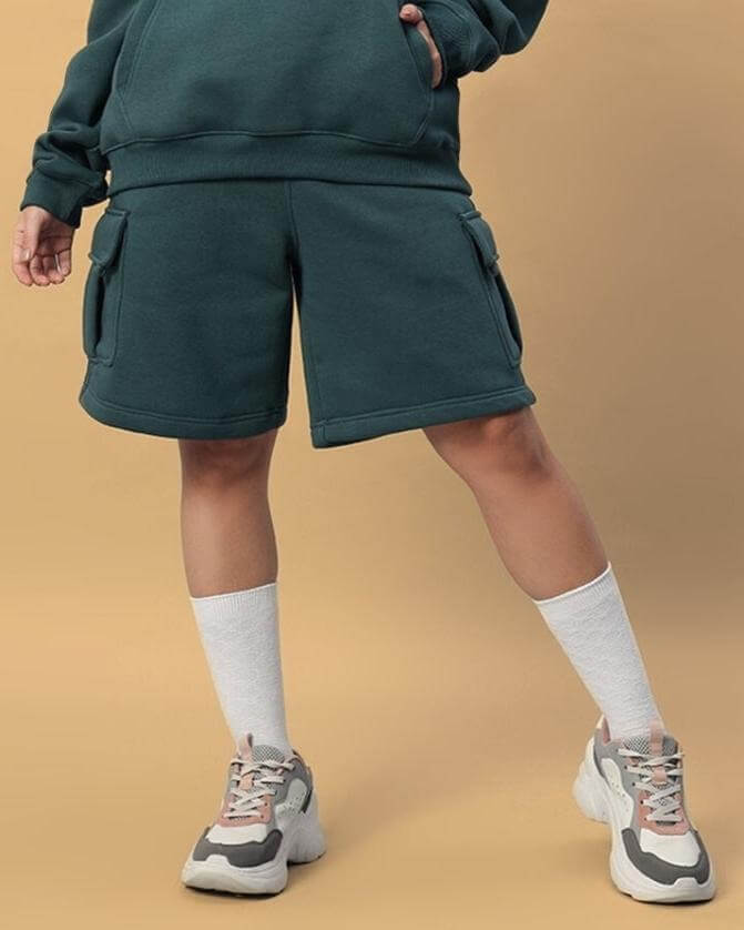Person wearing Women's Husky Fleece Solid Cargo Shorts in teal green with socks and sneakers.