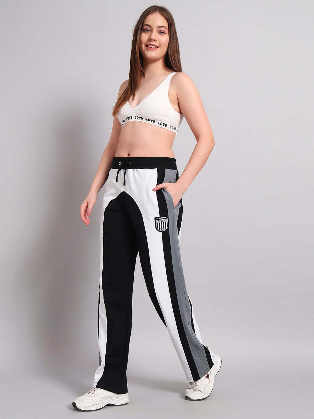 Model wearing Women's Jamison Color Block Joggers in Black Melange-Grey with relaxed fit, paired with a white sports bra, standing confidently.