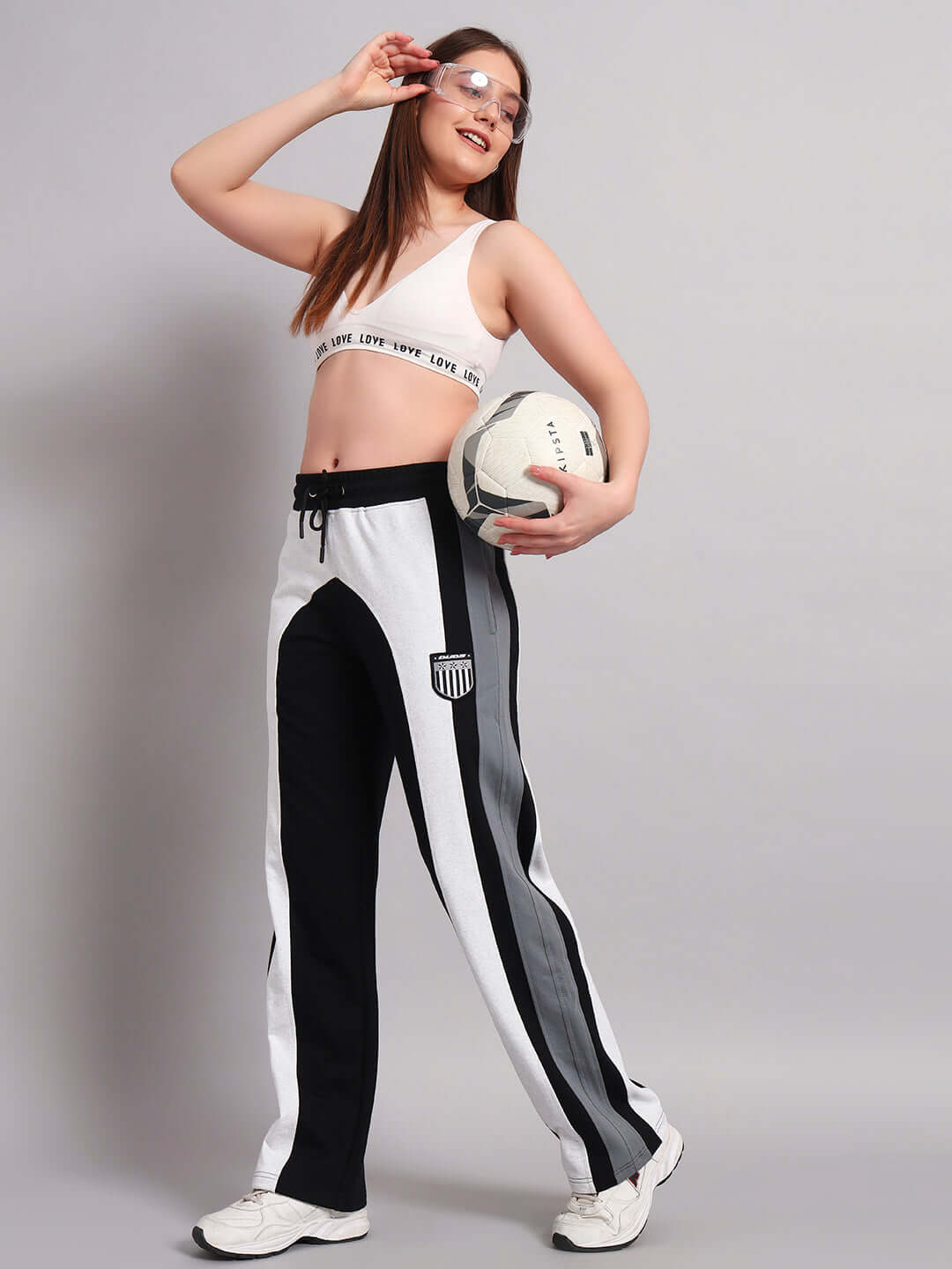 Woman wearing Jamison color block joggers in black melange-grey holding a soccer ball, showcasing a relaxed fit design.