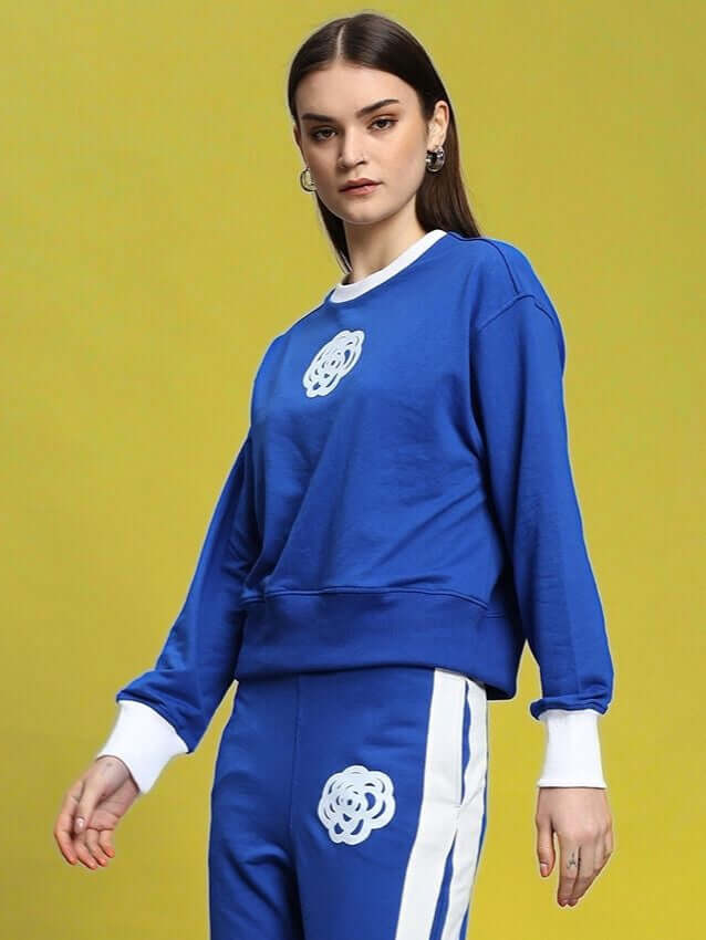 Woman wearing WOMEN'S JESSFLICK RELAXED FIT SWEATSHIRT ROYAL BLUE against a yellow background, showcasing casual style.