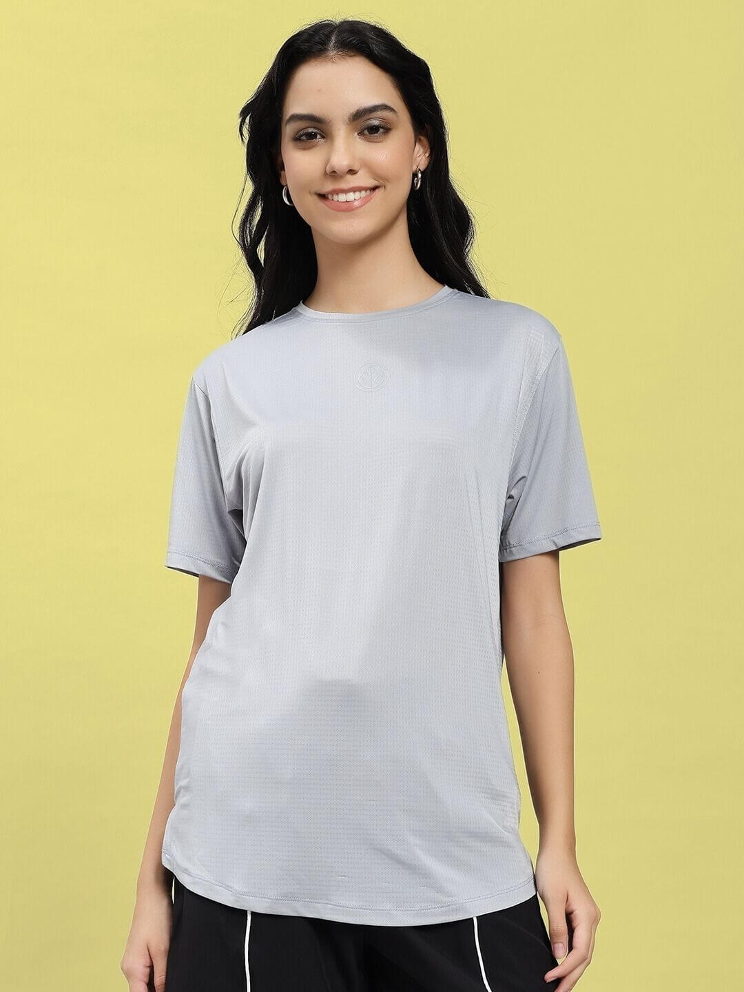 Woman wearing WOMEN JET RUN REGULAR FIT T-SHIRT GREY, showcasing a casual and modern look against a yellow background.