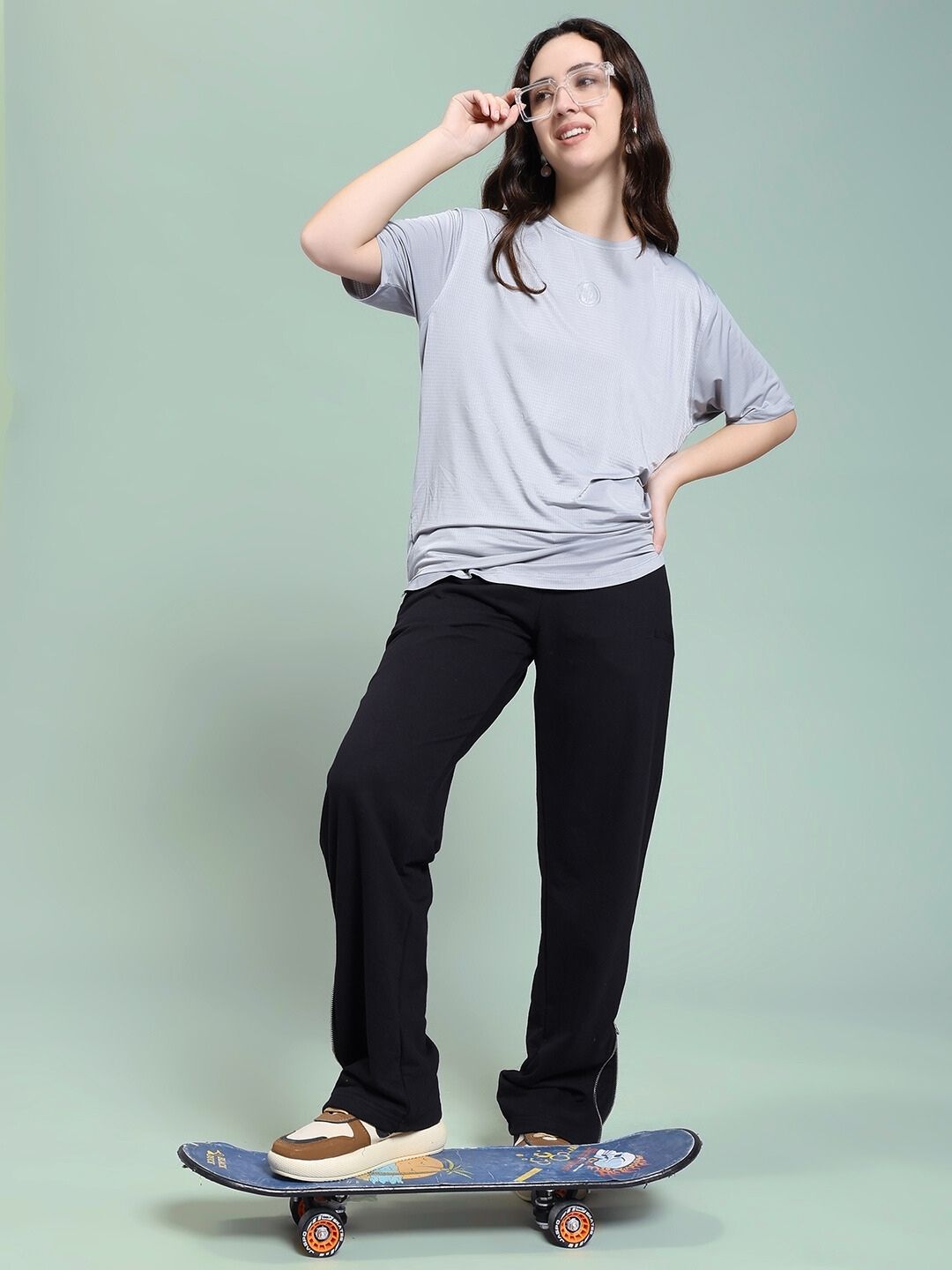 Model wearing WOMEN'S JOSS WINS RELAXED-FIT JOGGER BLACK, standing on a skateboard, posing confidently against a light blue background.
