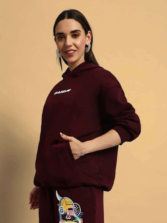 Woman wearing wine-colored jumbled fleece co-ord set with graphic details.