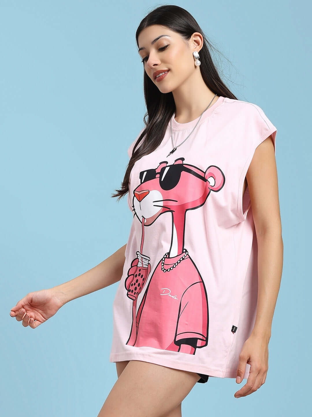 Woman wearing a pink T-shirt with Pink Panther print, featuring sunglasses and holding a beverage.