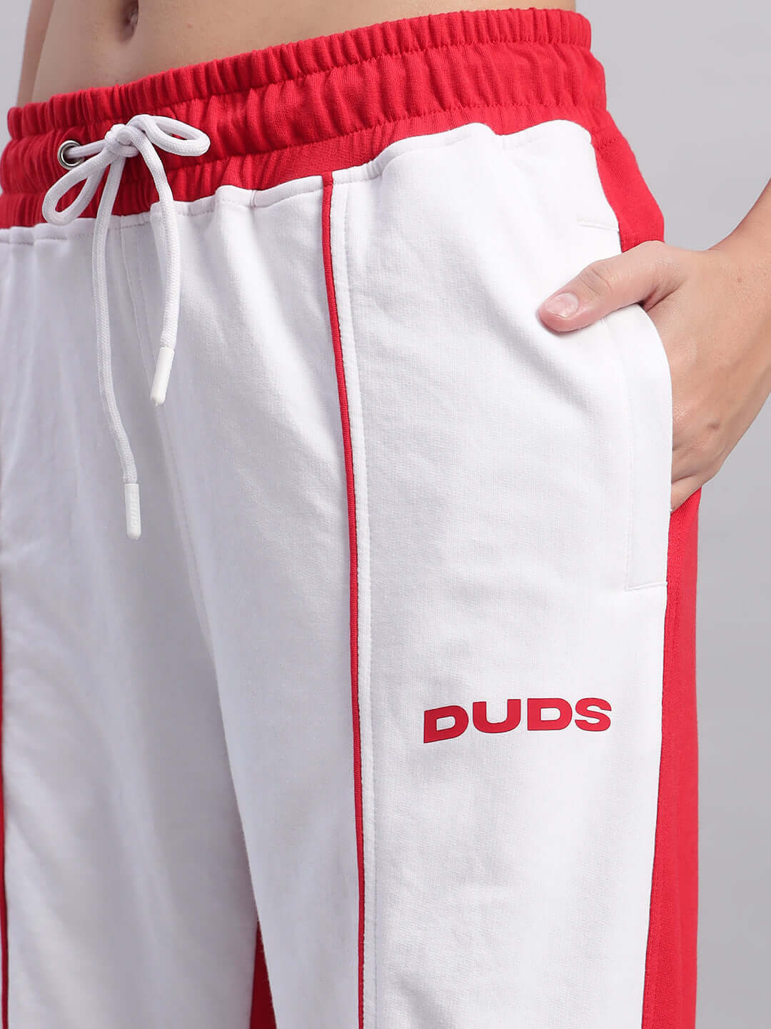 Close-up of women's white and red relaxed fit joggers with DUDS logo, featuring an adjustable waistband and stylish side pockets.