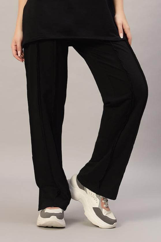Woman wearing black lamina side slit joggers with sneakers, perfect for casual wear. Stylish and comfortable for everyday use.