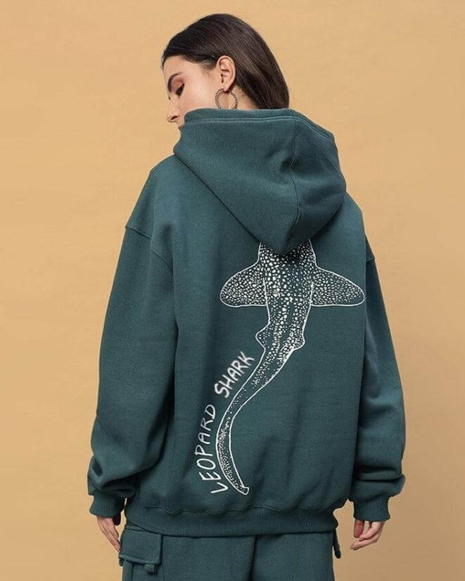 Back view of a woman wearing the WOMENS LEOPARD SHARK FLEECE HOODIE TEAL GREEN with shark graphic on back.