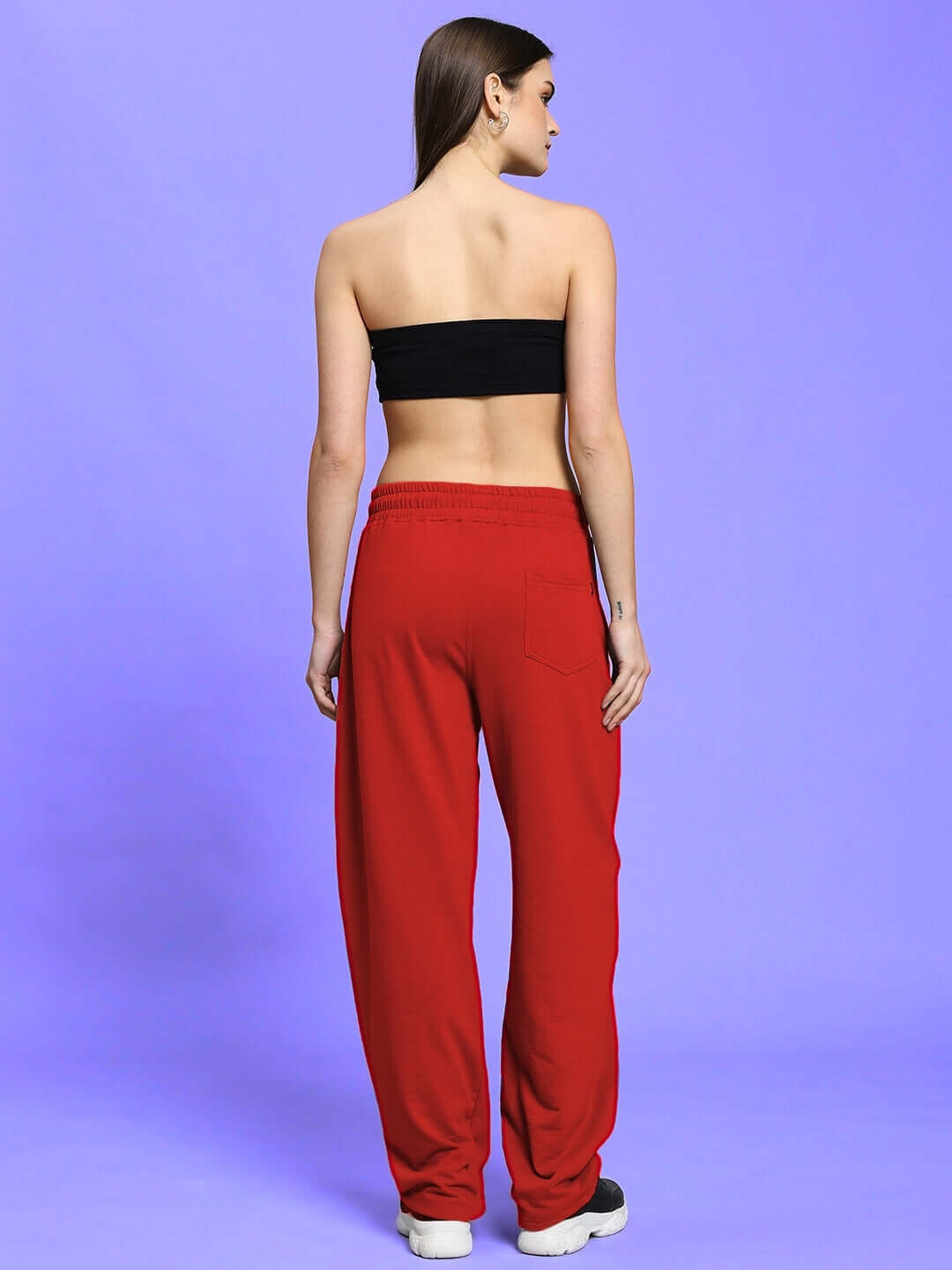Back view of WOMEN'S LIA CO-ORD SET BLACK RED with vibrant red pants and black top on a model against a purple background.