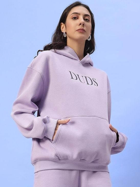 Woman wearing a lilac WOMEN RITZY FLEECE HOODIE LILAC by DUDS, showcasing stylish comfort with customizable fit options.