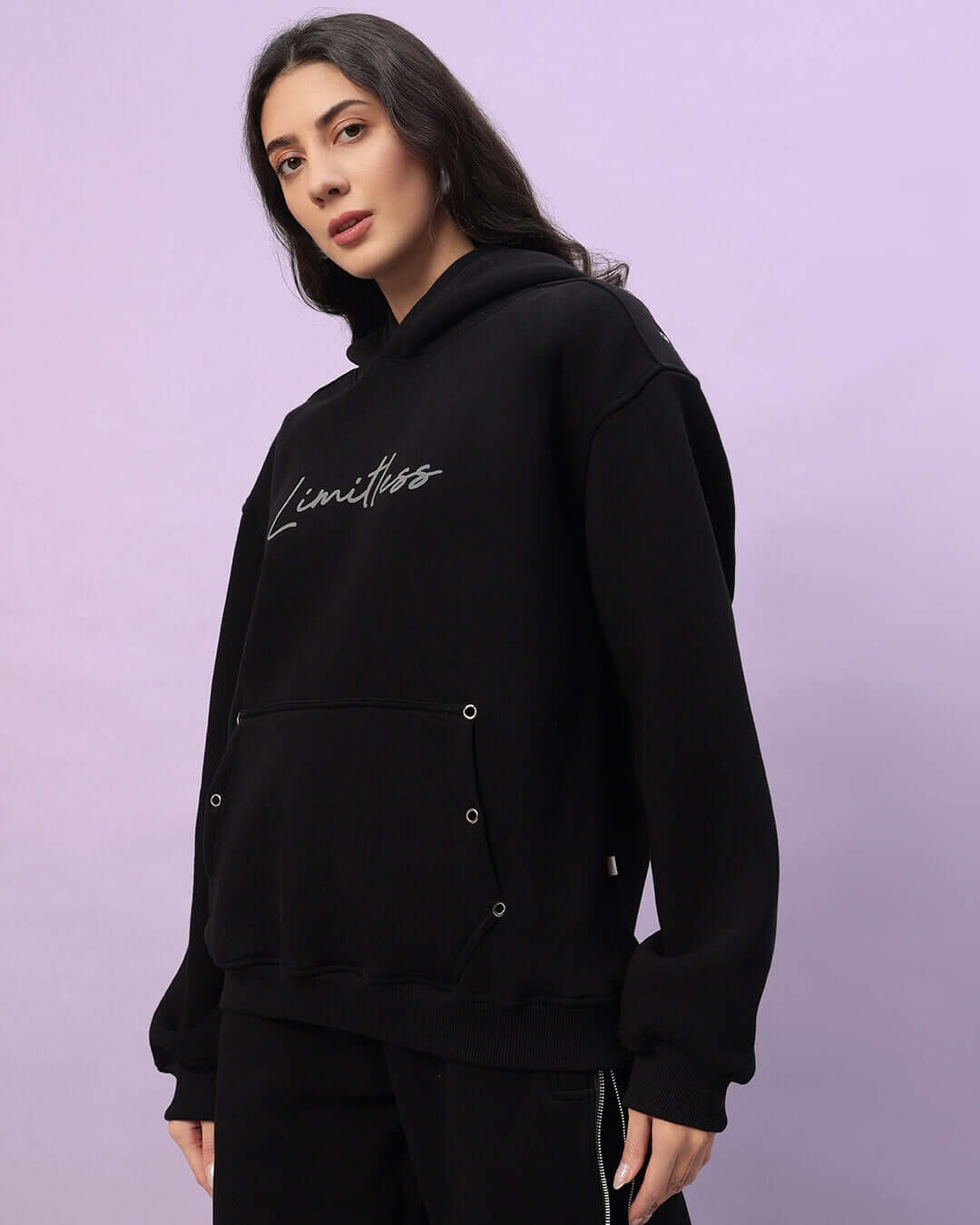 Woman wearing black Women’s Limitless Fleece Reflector Hoodie with reflector detailing, perfect for casual wear or outdoor activities.