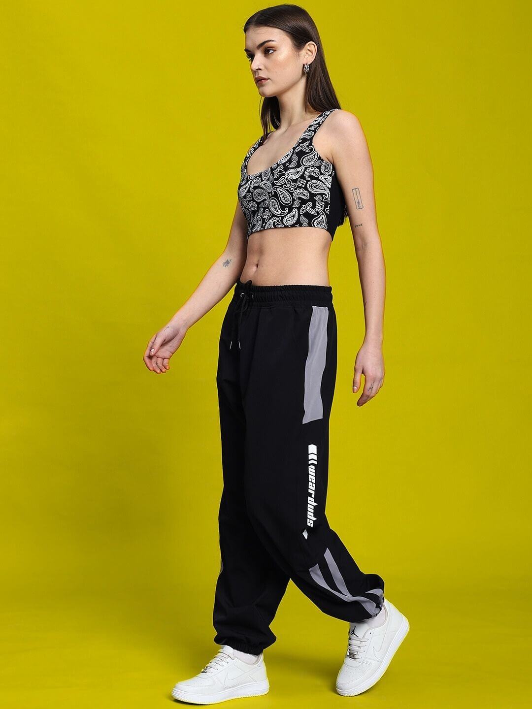 Model wearing WOMEN'S LINNA CO-ORD SET BLACK from WEAR DUDS, featuring a modern streetwear design against a vibrant yellow background.