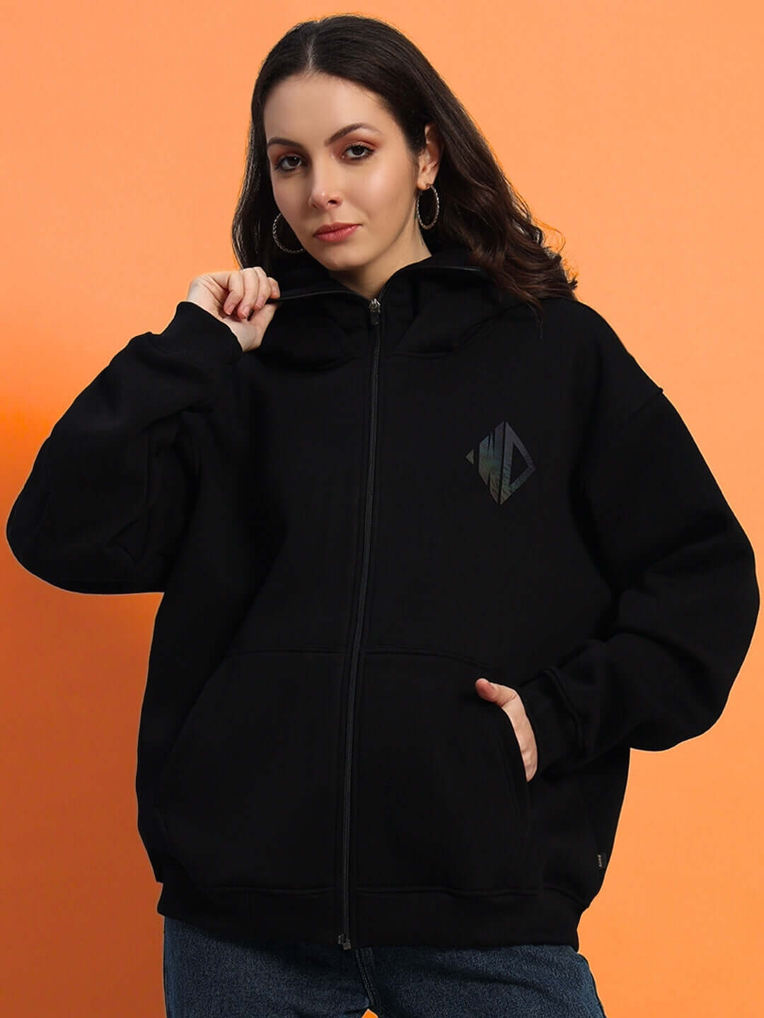 Woman wearing oversized black fleece hoodie against orange background