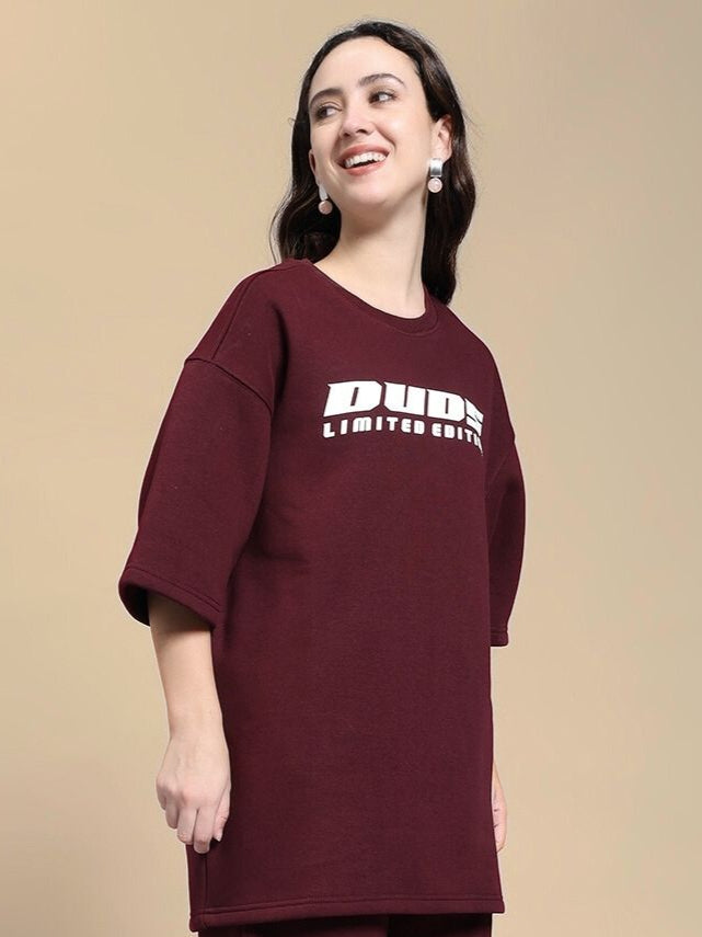 Woman wearing WOMEN'S SKODA FLEECE OVERSIZED T-SHIRT MAROON featuring bold logo, perfect for casual style.