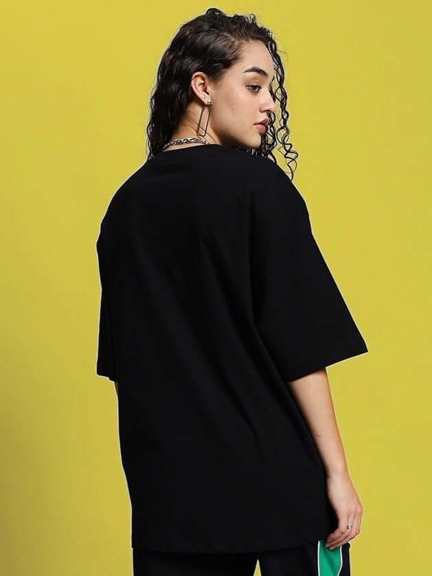 Woman wearing oversized black T-shirt made of premium cotton, showcasing comfortable and stylish casual wear. Background in vibrant yellow.