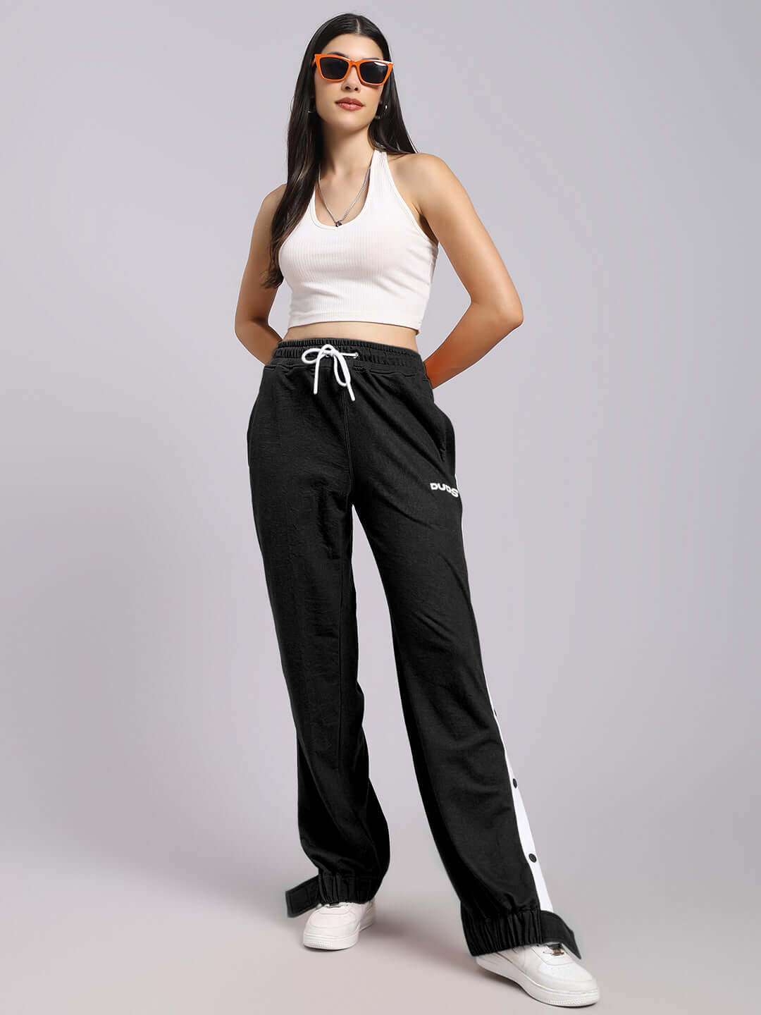 Woman wearing WOMENS MILLER RELAXED FIT JOGGERS BLACK with white top and sunglasses, showcasing casual and stylish fashion.