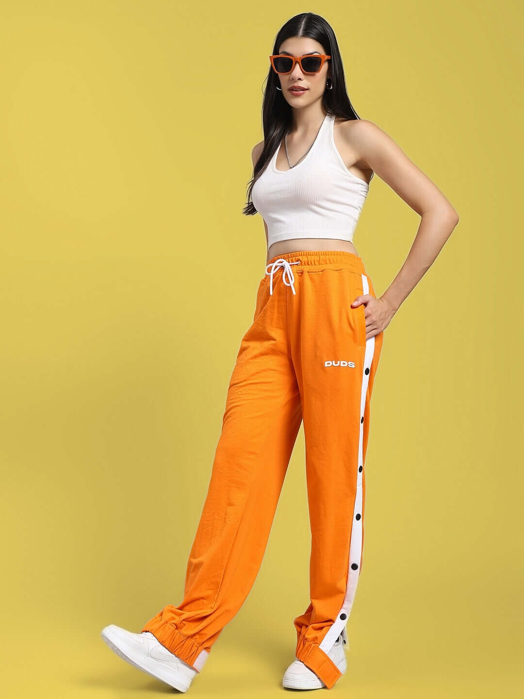 Woman wearing WOMENS MILLER RELAXED FIT JOGGERS ORANGE with sunglasses and white sneakers.