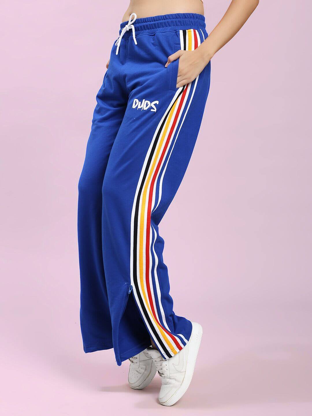 WOMEN MODERN EDGE MULTI-STRIPE CO-ORD SET ROYAL BLUE trousers with colorful side stripes on a pink background.