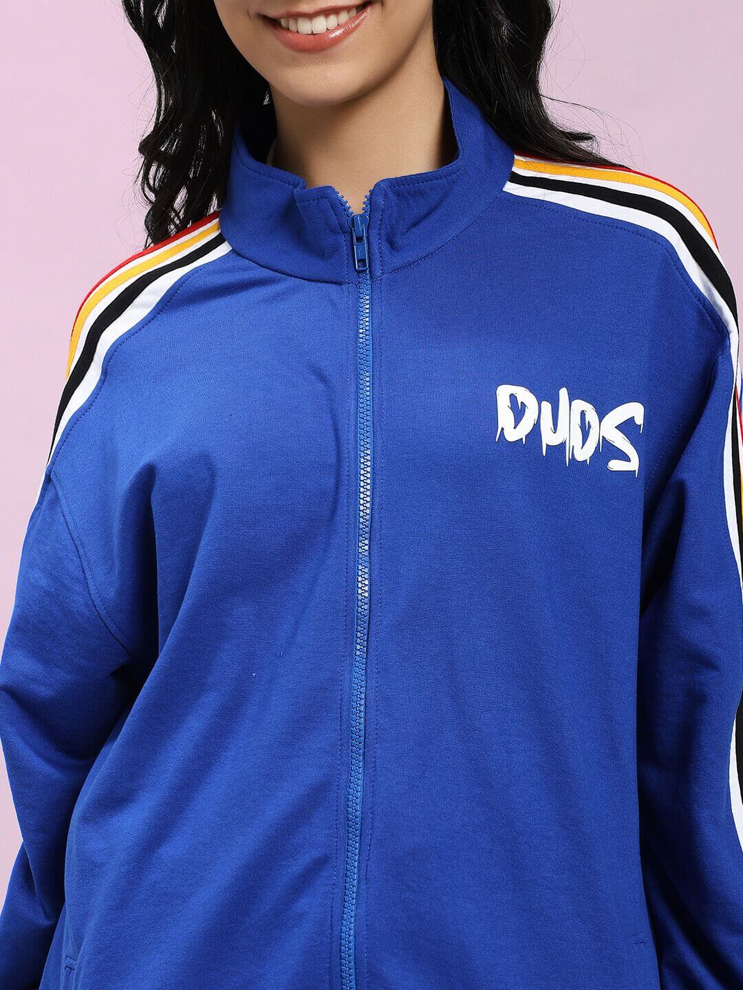 Close-up of woman wearing WOMEN MODERN EDGE MULTI-STRIPE JACKET ROYAL BLUE with bold stripes and zipper detail, embodying sporty style.