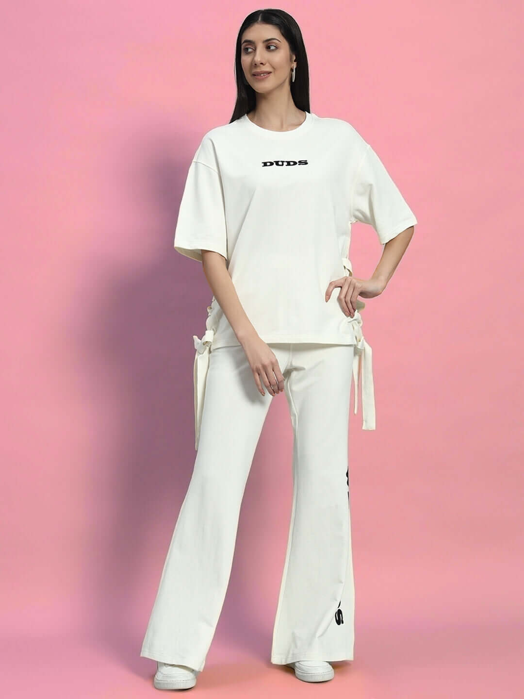 Women's Moon Night Co-Ord Set in off-white featuring relaxed fit joggers with drawstring and cotton-elastane blend, modeled on pink backdrop.