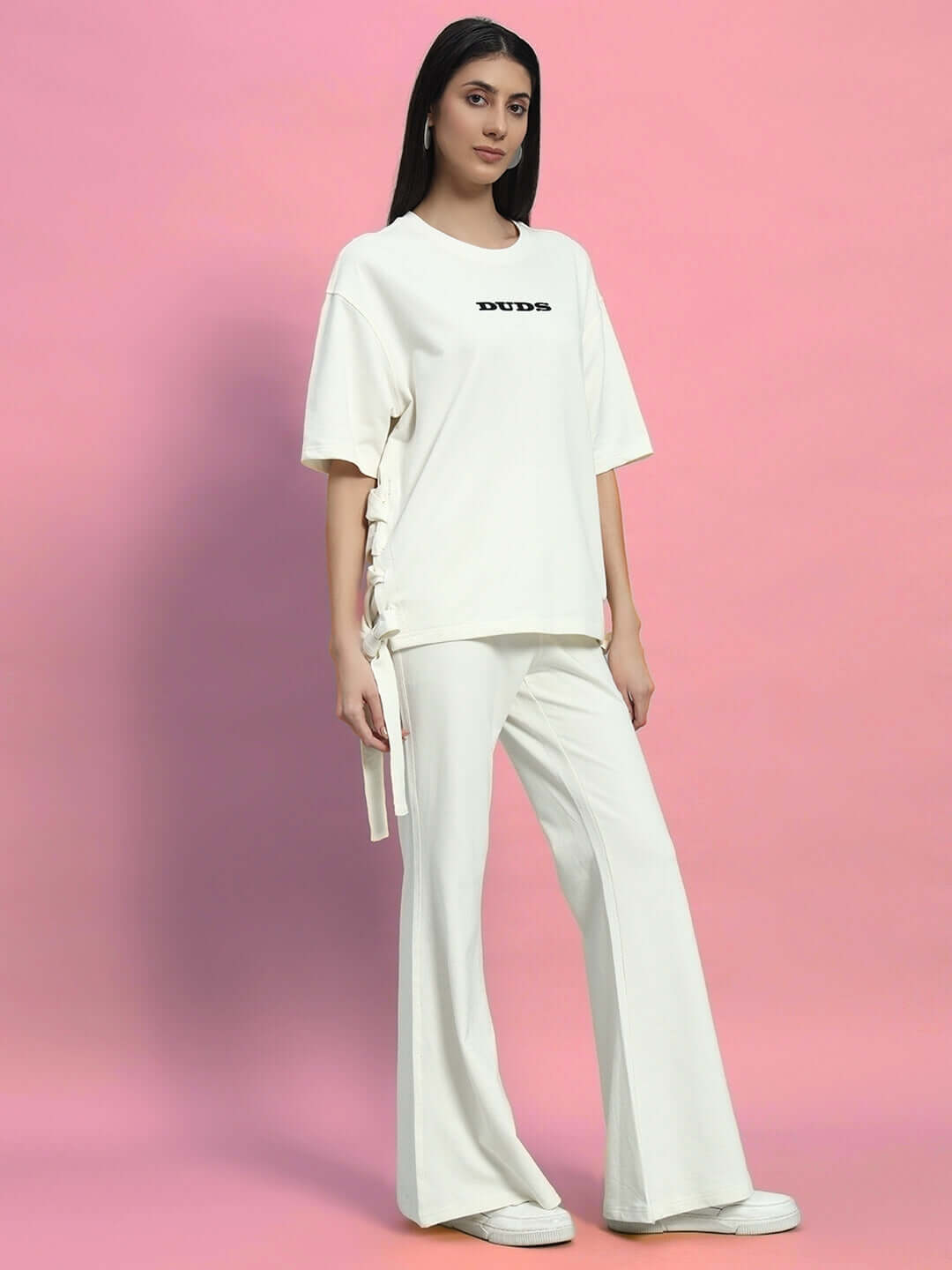 Woman wearing off-white Moon Night Co-Ord set with relaxed fit joggers and drawstring top against pink background.