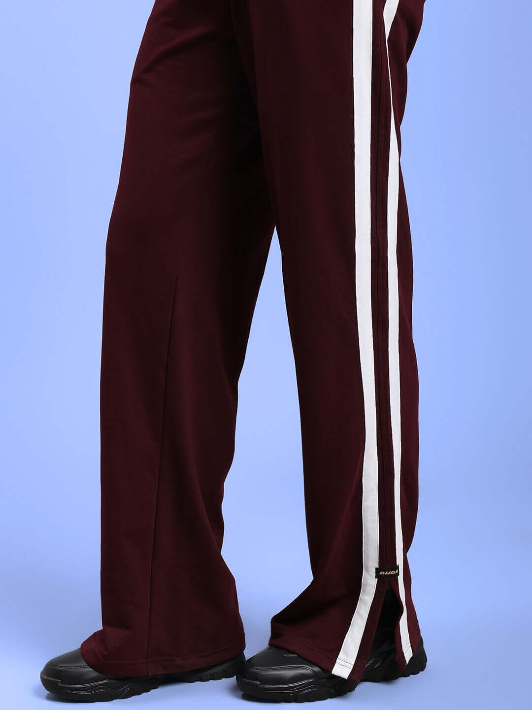 Maroon women's joggers with white side stripes, displayed on a light blue background.