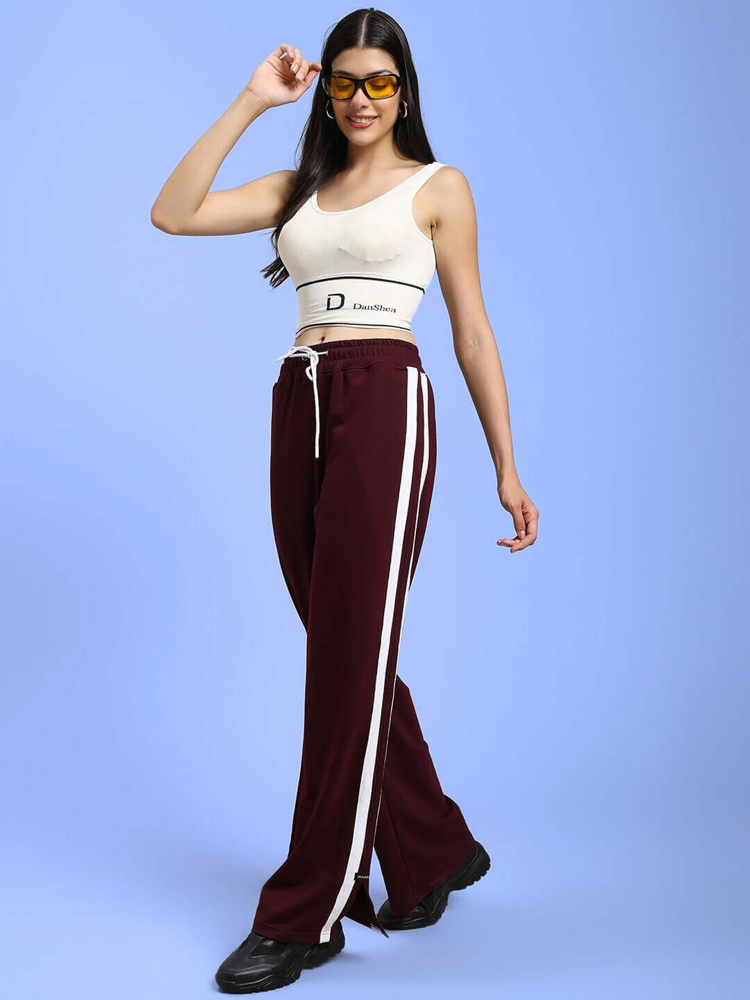 Woman wearing maroon relaxed fit joggers, styled with white top, showcasing fashion-forward and comfortable outfit.