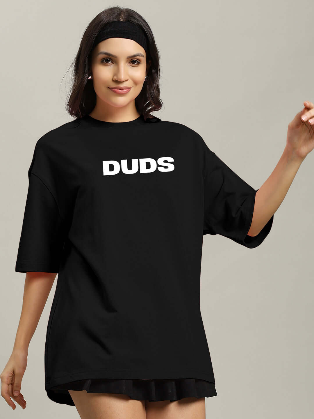 Woman wearing black oversized t-shirt with 'DUDS' logo, made from premium cotton blend, perfect for casual wear. Machine washable. Made in India.