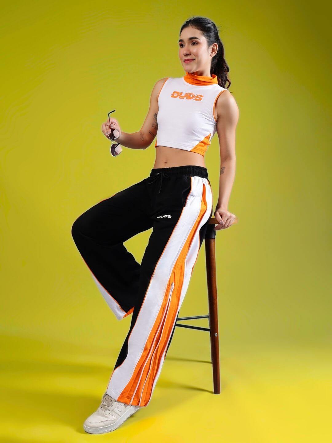 Stylish woman wearing white orange crop top by MYSKY, paired with trendy track pants. Perfect for casual outings.
