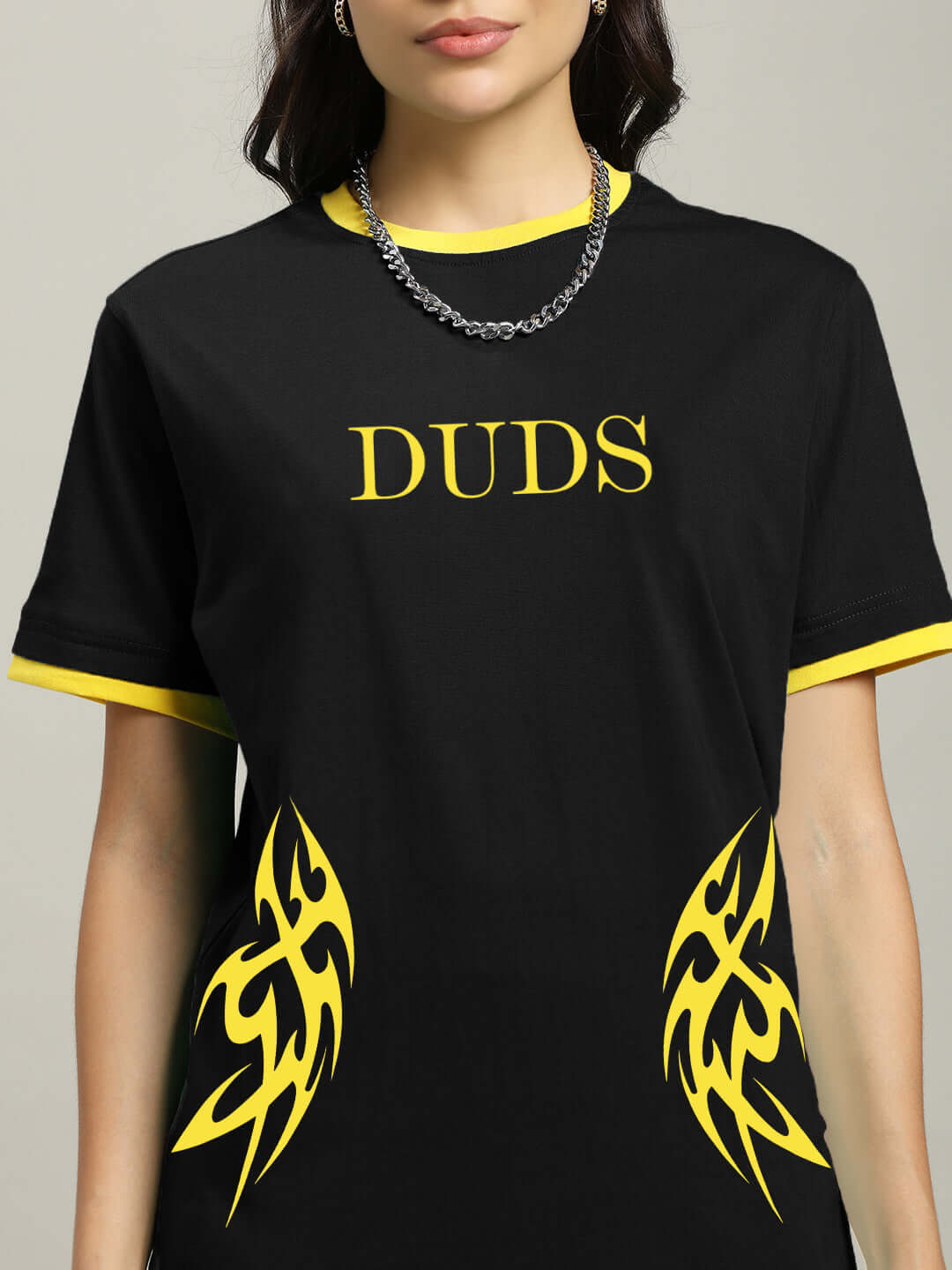 Black women's regular fit t-shirt with yellow accents and graphic design, featuring 'DUDS' text on chest, modeled in close-up view.