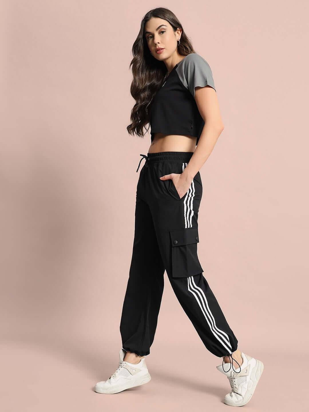 Woman wearing black Nova relaxed fit cargo pants with pockets and drawstring, paired with casual top and sneakers.
