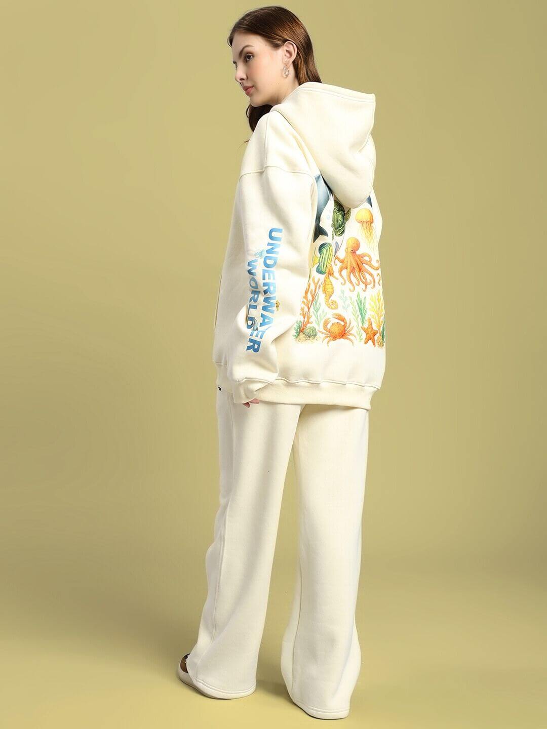 Model wearing WOMEN OCEAN BUDDIES FLEECE CO-ORD SET OFF-WHITE with sea-inspired graphics."}